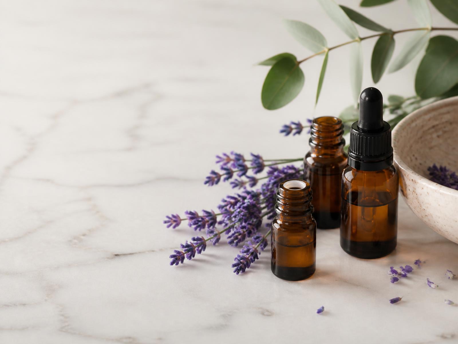 Frascos âmbar de óleos essenciais com lavanda sobre mármore